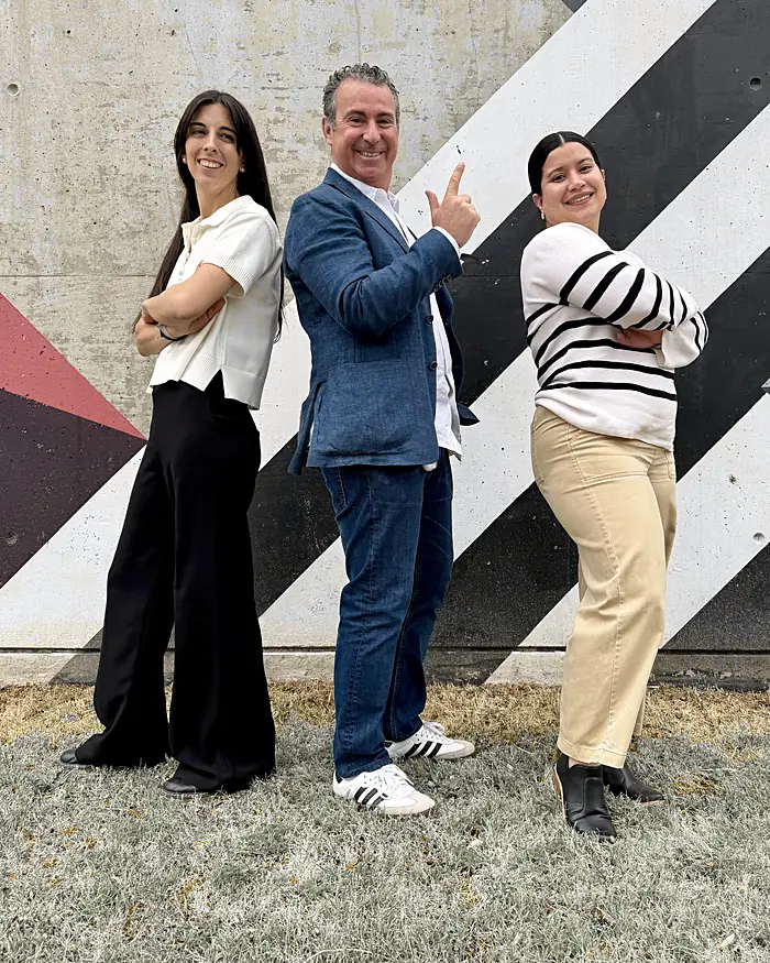 El equipo de Velo, sonriente, posando espalda con espalda frente a un mural
